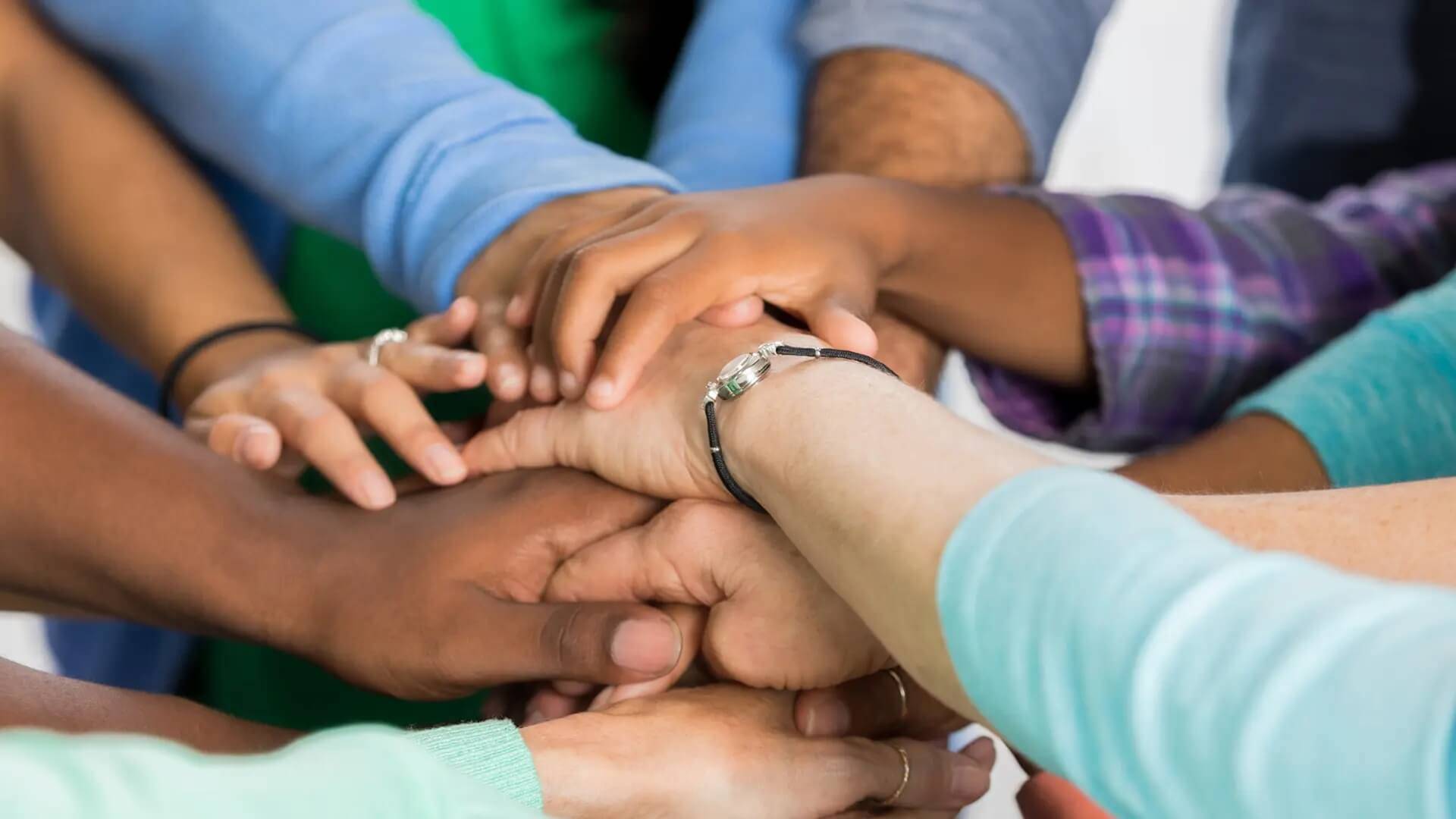 Ehrenamtliches Engagement Mehrere Hände sind in der Mitte übereinander gelegt.