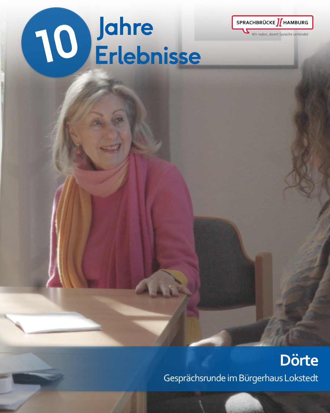 Gesprächsleiterin Dörte sitzt an der Ecke eines Schreibtischs während der Gesprächsrunde am Standort Lokstedt und blickt lächelnd nach rechts. Am rechten Bildrand ist die Silhouette einer anderen Frau zu erkennen.