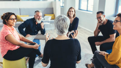 Mehrere Personen sitzen in einem Kreis und unterhalten sich lebhaft.